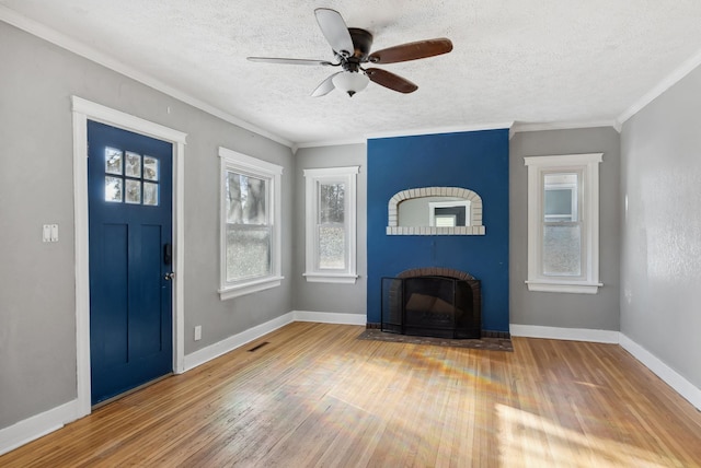 entryway featuring a textured ceiling, ornamental molding, ceiling fan, a fireplace, and hardwood / wood-style floors