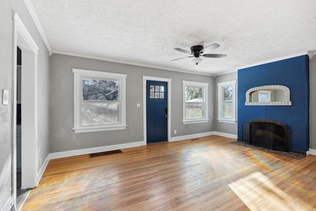 foyer entrance featuring hardwood / wood-style flooring, ornamental molding, plenty of natural light, and a fireplace