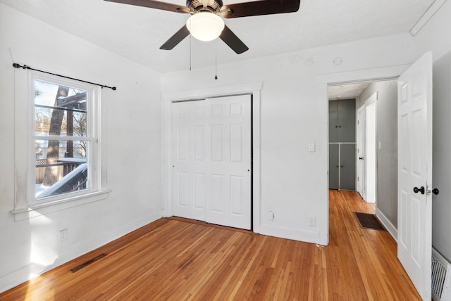 unfurnished bedroom featuring ornamental molding, ceiling fan, light hardwood / wood-style floors, and a closet