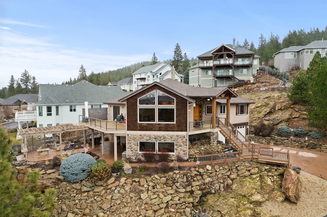 rear view of house with a wooden deck, a pergola, and a patio