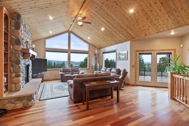 living area featuring light wood finished floors, wood ceiling, a fireplace, and high vaulted ceiling