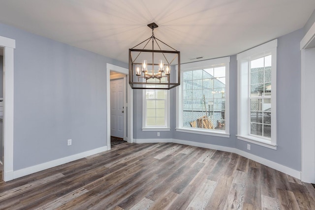 unfurnished dining area with an inviting chandelier and dark hardwood / wood-style floors