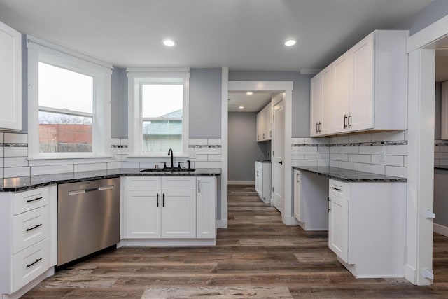 kitchen with sink, dark stone countertops, white cabinets, stainless steel dishwasher, and dark wood-type flooring