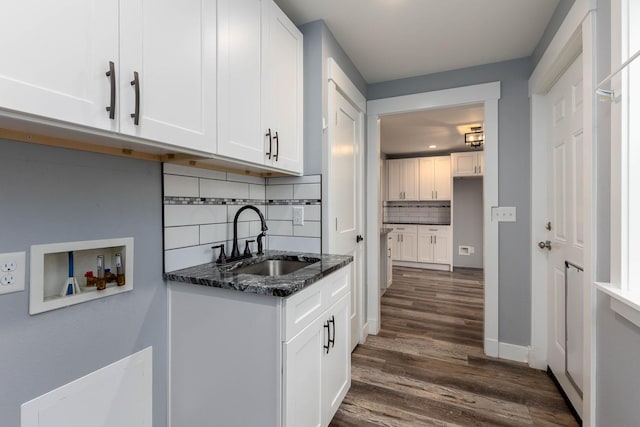 kitchen with dark stone countertops, dark hardwood / wood-style flooring, sink, and white cabinets