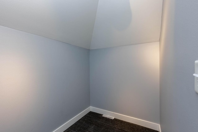 carpeted spare room featuring vaulted ceiling