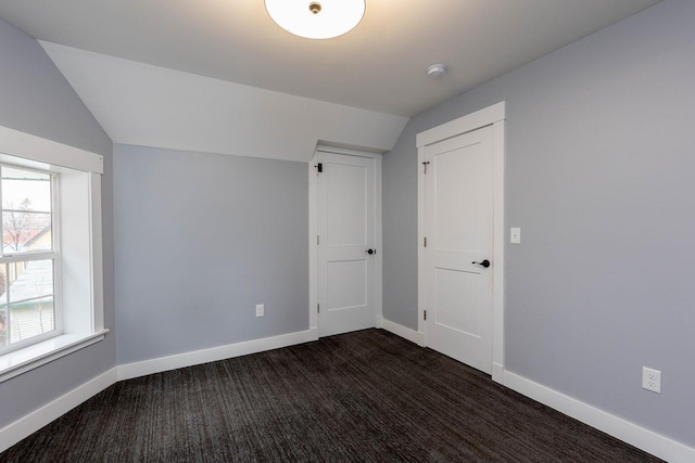 interior space featuring lofted ceiling and dark colored carpet