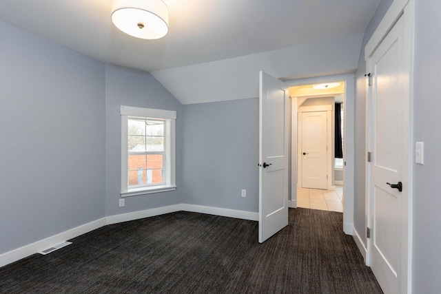 unfurnished bedroom featuring dark carpet and vaulted ceiling