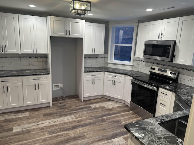 kitchen featuring white cabinetry, dark wood-type flooring, dark stone countertops, and appliances with stainless steel finishes