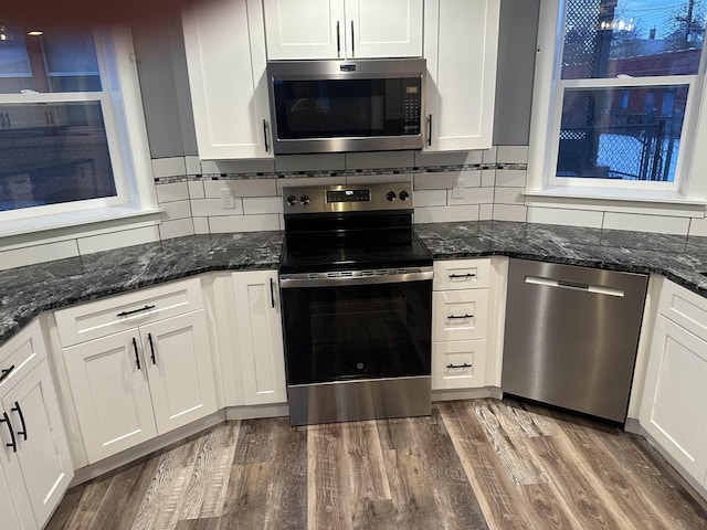 kitchen featuring white cabinetry, stainless steel appliances, dark wood-type flooring, and dark stone counters