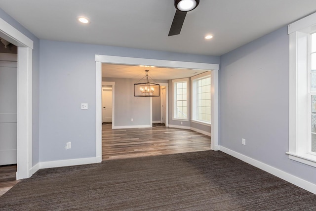 carpeted spare room with ceiling fan with notable chandelier