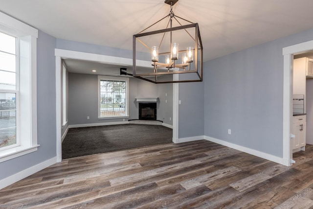 unfurnished living room featuring an inviting chandelier and dark hardwood / wood-style floors