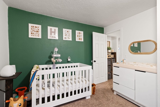 bedroom with a nursery area, light colored carpet, and a textured ceiling