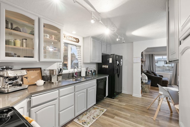 kitchen featuring sink, white cabinetry, a textured ceiling, light wood-type flooring, and black appliances