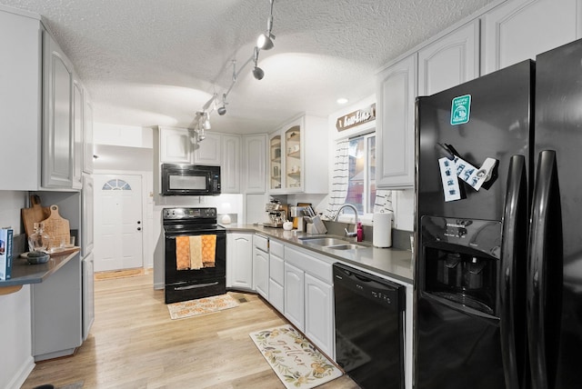 kitchen featuring sink, black appliances, a textured ceiling, white cabinets, and light wood-type flooring