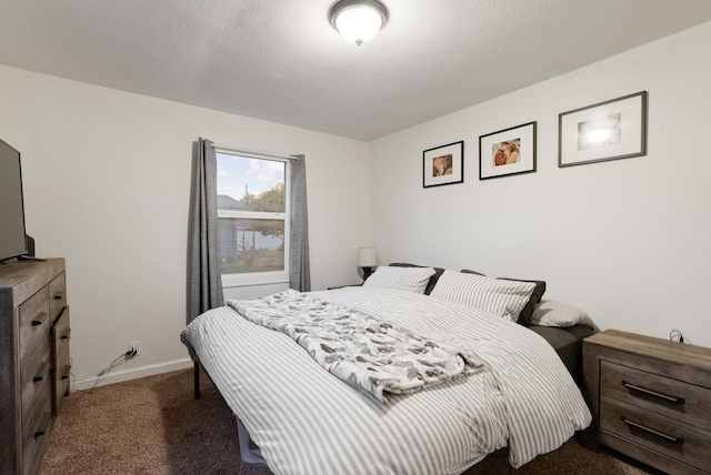 bedroom with a textured ceiling and dark colored carpet