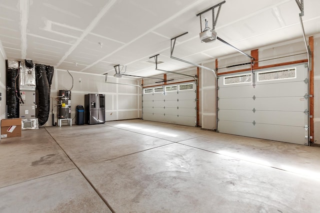 28411 N Milan Rd, Chattaroy, WA 99003 - garage with a garage door opener, stainless steel refrigerator with ice dispenser, gas water heater, and heating unit