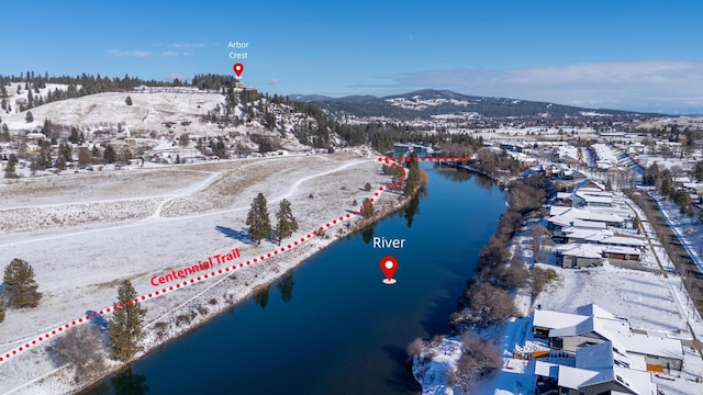 snowy aerial view featuring a water and mountain view