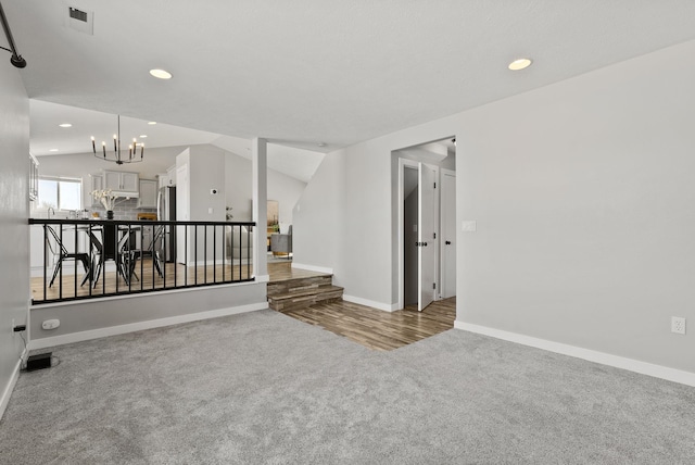 unfurnished room featuring lofted ceiling, a chandelier, and light carpet