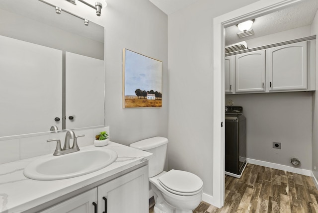 bathroom featuring toilet, wood-type flooring, washer / clothes dryer, and vanity