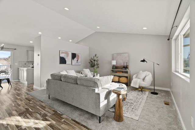 living room featuring lofted ceiling, hardwood / wood-style floors, and a notable chandelier