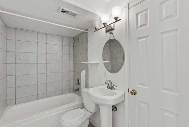 full bathroom featuring tiled shower / bath, sink, a textured ceiling, and toilet