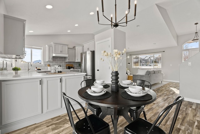 dining space with vaulted ceiling and light wood-type flooring