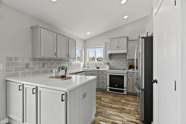 kitchen featuring range with electric cooktop, vaulted ceiling, stainless steel refrigerator, gray cabinetry, and light stone counters