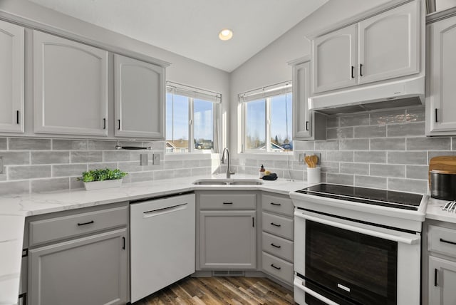 kitchen featuring lofted ceiling, sink, dishwashing machine, light stone countertops, and electric stove