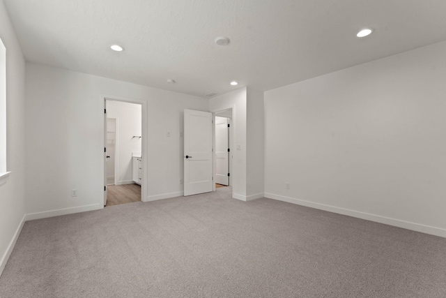 unfurnished bedroom with light colored carpet and ensuite bathroom