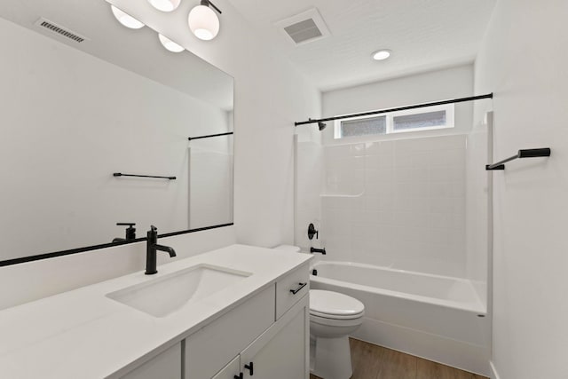 full bathroom with vanity, tiled shower / bath, hardwood / wood-style floors, and toilet