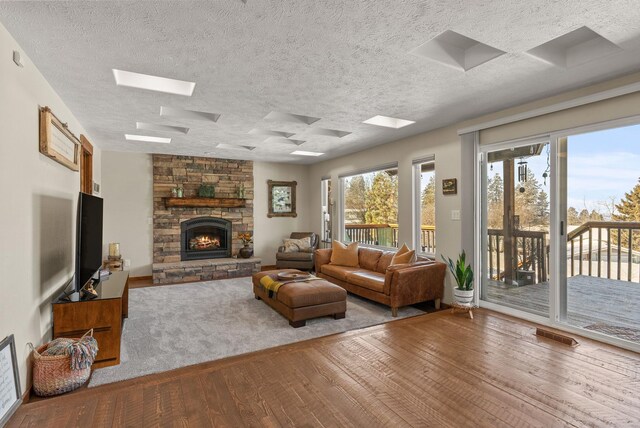 living room with wood-type flooring, a stone fireplace, and a textured ceiling