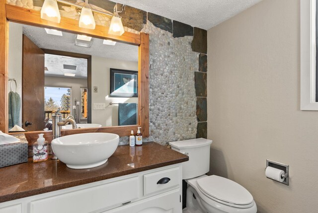 bathroom featuring vanity, toilet, and a textured ceiling