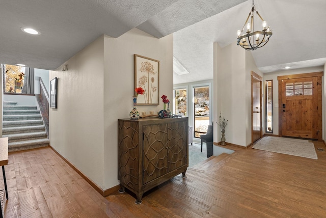 entryway featuring hardwood / wood-style flooring, vaulted ceiling, and an inviting chandelier