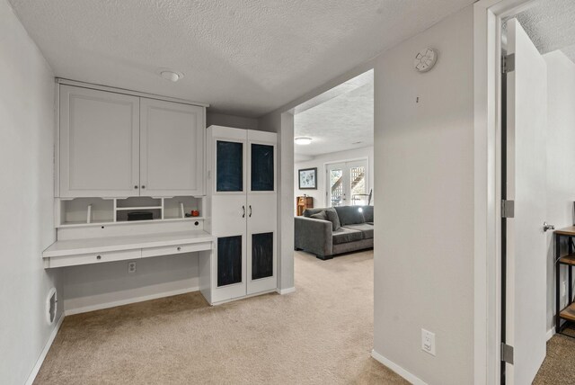 interior space with light colored carpet, french doors, and a textured ceiling