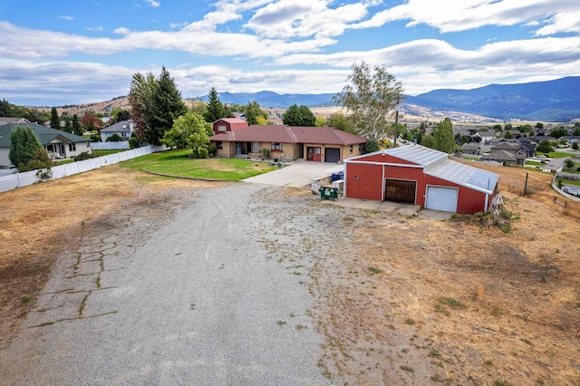 ranch-style house with a garage, a mountain view, an outbuilding, and a front lawn