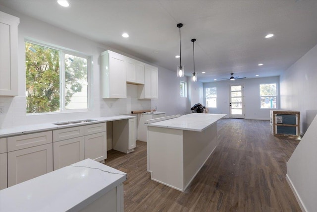 kitchen with white cabinetry, dark hardwood / wood-style flooring, a kitchen island, and backsplash