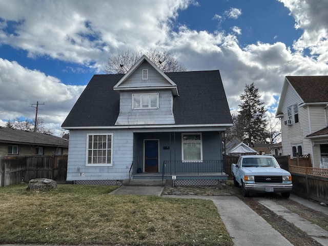 bungalow-style house with a porch, concrete driveway, a front lawn, and fence