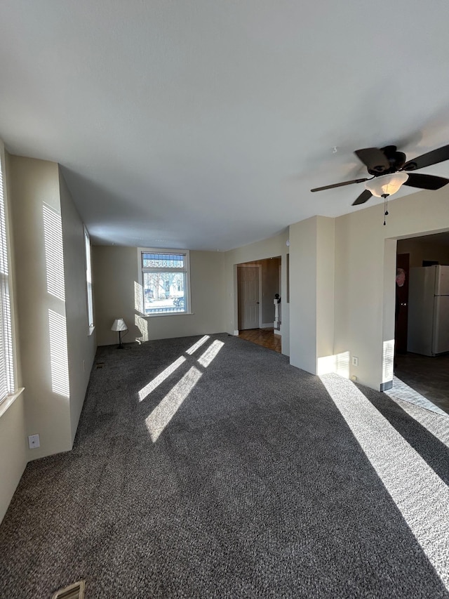 unfurnished living room featuring dark carpet and ceiling fan