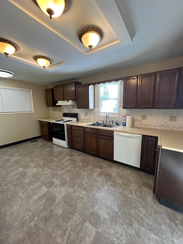 kitchen with a tray ceiling, white dishwasher, a sink, range with electric cooktop, and light countertops