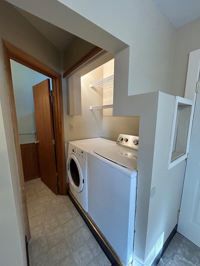 clothes washing area with separate washer and dryer, light floors, and laundry area