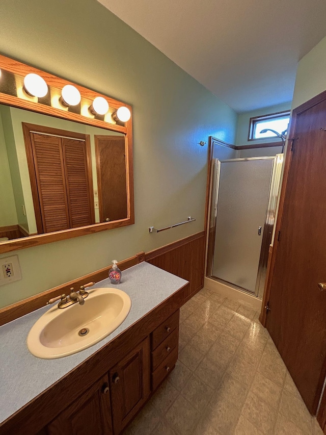 full bathroom with a shower stall, wood walls, wainscoting, tile patterned floors, and vanity