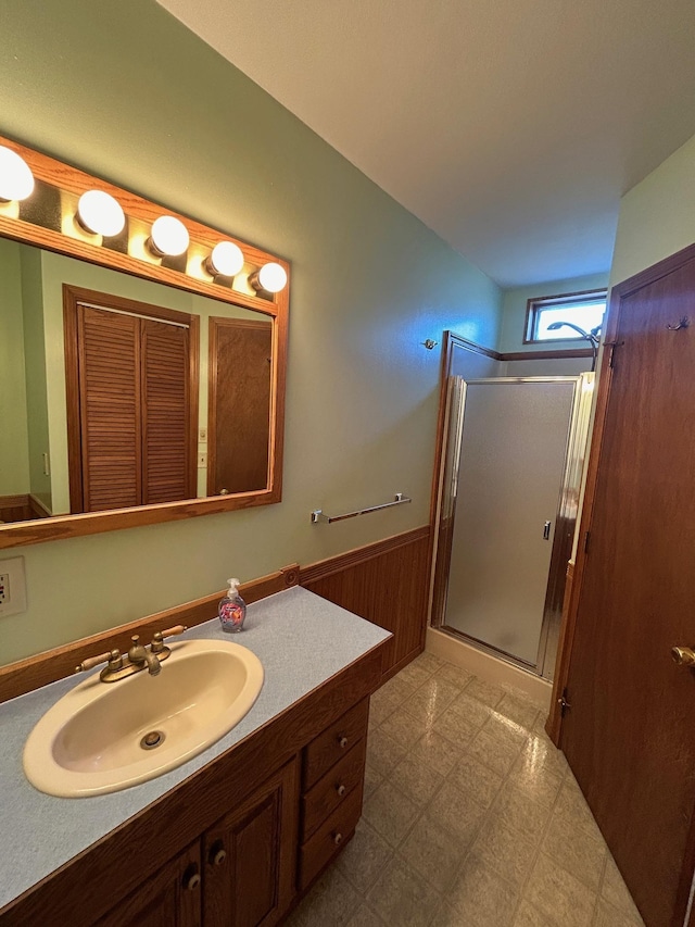 full bath featuring tile patterned floors, a wainscoted wall, wood walls, a shower stall, and vanity