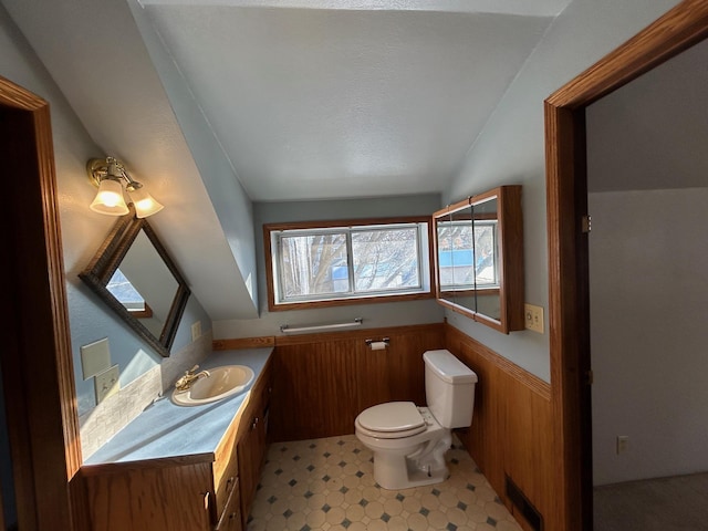 bathroom with a wainscoted wall, visible vents, toilet, lofted ceiling, and vanity