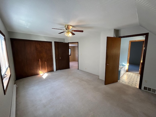 unfurnished bedroom with a ceiling fan, visible vents, a baseboard radiator, light carpet, and two closets