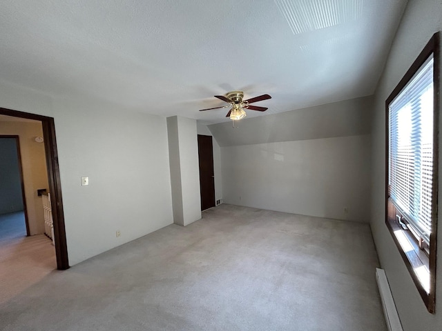 unfurnished room featuring a ceiling fan, vaulted ceiling, a textured ceiling, light carpet, and baseboard heating