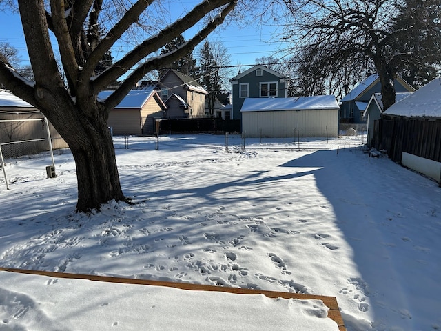 snowy yard with an outbuilding and fence