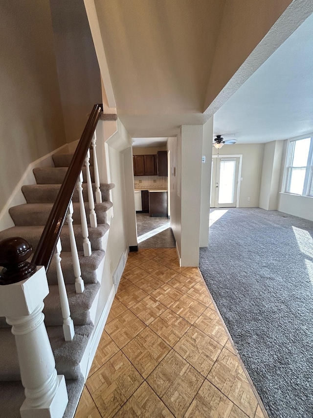 stairway with visible vents, carpet floors, and a ceiling fan