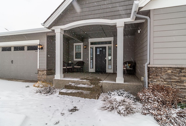 snow covered property entrance with a garage