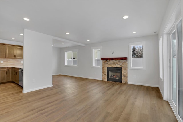 unfurnished living room featuring plenty of natural light, a fireplace, and light hardwood / wood-style floors