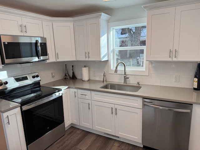 kitchen featuring appliances with stainless steel finishes, tasteful backsplash, white cabinetry, sink, and dark hardwood / wood-style flooring